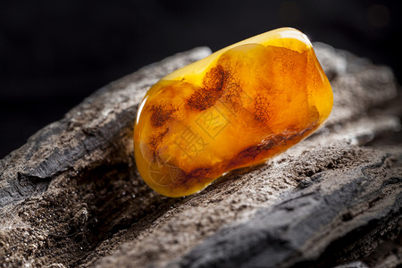 黑琥珀李天然琥珀 黄色不透明的天然琥珀 在大片黑石头木头上反射分层材料黄油宝石化石裂缝蜂蜜矿物琥珀色背景