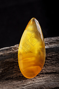 黑琥珀李天然琥珀 黄色不透明的天然琥珀 在大片黑石头木头上珠子琥珀色裂缝分层矿物珠宝宏观材料黄油宝石背景