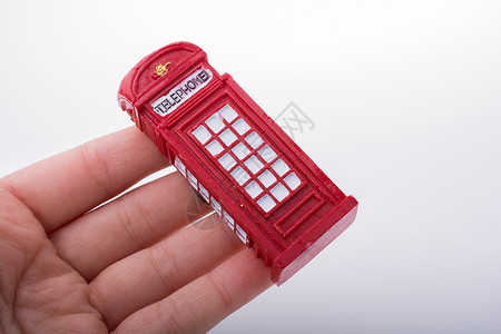 手持白色背景的电话亭 手持英语红色电话盒子公用电话城市背景图片