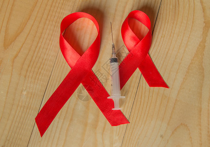 网络安全宣传展板木质背景中的红丝带和注射器意识 世界抗击艾滋病日 12 月促进公众对艾滋病病毒感染者的支持癌症斗争宣传治愈网络安全机构疾病仪式缺背景