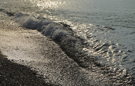 清晨日出海卵石海滩上闪亮的银色水海洋蓝色岩石阳光卵石反射水滴石头墙纸泡沫背景图片