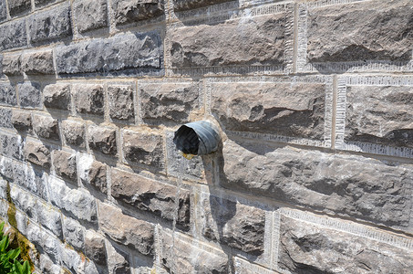 用灰砖墙从管里抽出的水石头管子管道排水灰色背景图片