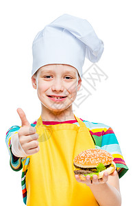 快乐的男孩以帽子和围裙做饭 用芝士汉堡和小菜高清图片