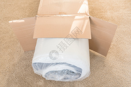 弹簧包在地毯地底背景上拆箱的 滚包装弹簧床垫房子家具泡沫公寓开箱地面塑料房间卧室纸箱背景