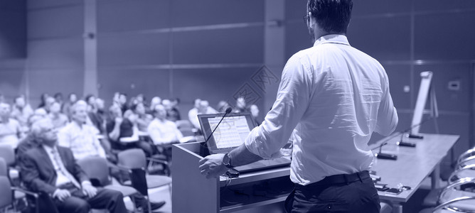 在商务活动上演讲的公开发言人电脑教育男性观众报告学习会议厅知识手势精神背景图片