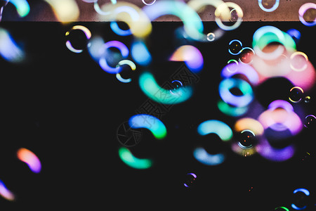 深色背景上的七彩泡泡液体肥皂反射桌面气球圆圈黑暗乐趣孩子场地背景