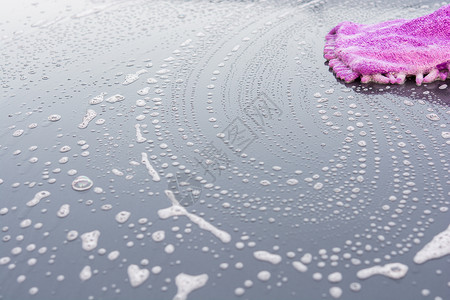汽车车衣使用手套洗车清洁他的汽车的特写镜头海绵男性肥皂男人打扫职业紫色反光衣挡风玻璃工人背景