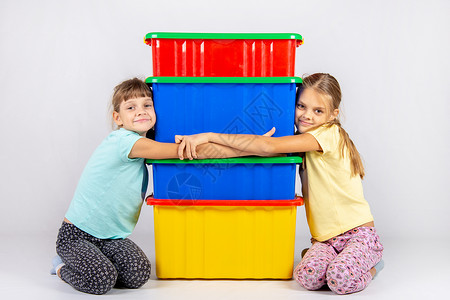 两个女孩拥抱大塑料盒高清图片