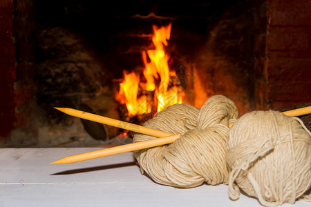 火针冬季概念概念 以木本为背景 用家里的火来编织羊毛和三角针家庭火焰针织经编木头袜子椅子背景