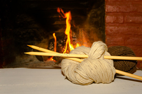 火针冬季概念概念 以木本为背景 用家里的火来编织羊毛和三角针火焰木头椅子经编家庭袜子针织背景