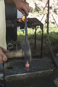 铁匠在铁砧上锻打铁锤子古董红色铁匠铺马蹄铁匠工人工作作坊店铺金属背景图片
