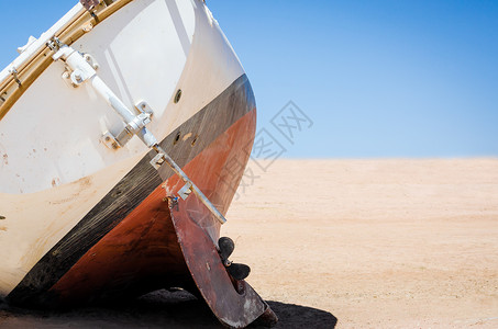 古老的破旧游艇躺在埃及沙漠沙滩上背景图片