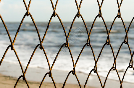 海滩和海洋背景的网状铁丝栅栏背景图片
