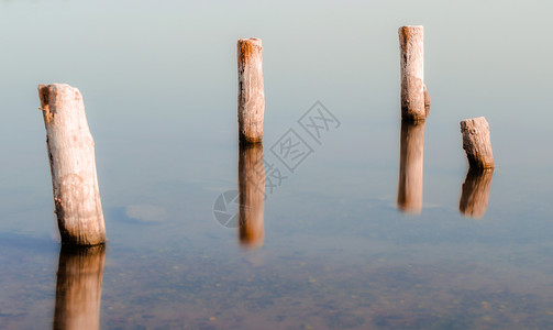 水的平静表面中的木板柱气候海景反射环境季节海洋背景图片