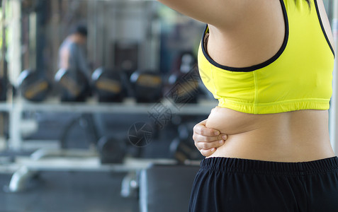 特写女人持有过多的脂肪下背部 女人超重内衣运动胸罩女士组织手臂女性肥胖身体暴饮暴食背景图片