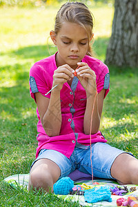 女孩在野外野餐上用编织针织毛衣高清图片