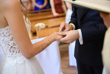 新郎装新娘和新郎在婚礼上把结婚戒指戴在手指上套装女士金子推杆钻石教会生活丈夫成人珠宝背景