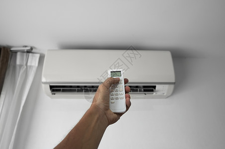 空调加氟使用遥控器的人的手 手持 rc 和调节安装在白墙上的空调温度 室内舒适温度 健康理念和节能微风气候冷却房间活力护发素控制办公室加背景