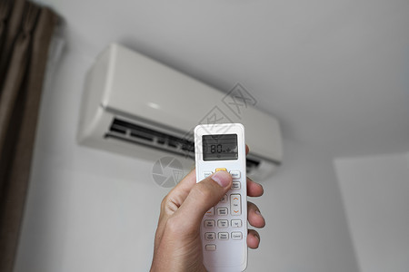 节能空调使用遥控器的人的手 手持 rc 和调节安装在白墙上的空调温度 室内舒适温度 健康理念和节能手臂加湿器微风按钮冷却器扇子活力气候技背景