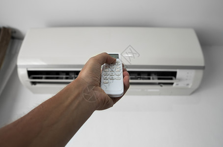 节能空调使用遥控器的人的手 手持 rc 和调节安装在白墙上的空调温度 室内舒适温度 健康理念和节能扇子技术手臂通风力量冷却器加湿器微风状背景