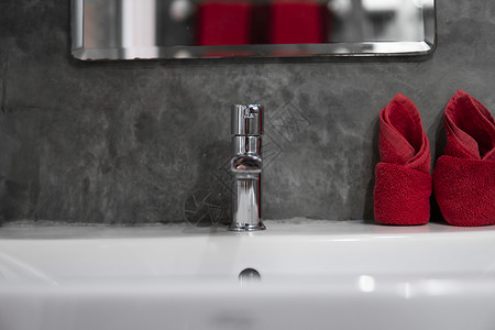 带洗脸盆水槽的现代不锈钢龙头 上面有两条红色毛巾 柜台浴室内部现代 豪华时尚的设计浴室配有混凝土风格的墙壁合金财产公寓卫生酒店建背景图片