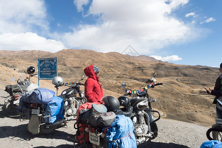 极限海豚帮印度妇女旅行者Trikker和Biker站在摩托车旁 远足喜马拉雅山区高山地区外出并探索当地山丘站 冒险旅游 2019年10月背景