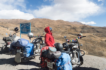极限海豚帮印度妇女旅行者Trikker和Biker站在摩托车旁 远足喜马拉雅山区高山地区外出并探索当地山丘站 冒险旅游队 2019年10月背景