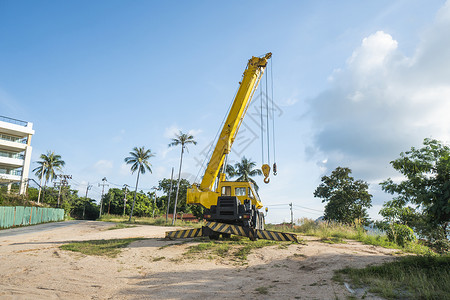 有上升的伸缩臂的黄色汽车起重机在户外 建筑工地上的移动式建筑起重机 起重机在施工大楼下等待工作 重工业机器柴油机勃起地面技术升降背景图片