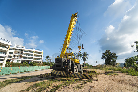 有上升的伸缩臂的黄色汽车起重机在户外 建筑工地上的移动式建筑起重机 起重机在施工大楼下等待工作 重工业机械卡车车辆勃起力量机器装背景图片