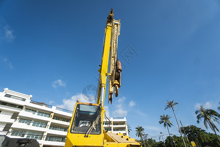 容量大有上升的伸缩臂的黄色汽车起重机在户外 建筑工地上的移动式建筑起重机 起重机在施工大楼下等待工作 重工业运输绳索柴油机活动地面天空背景