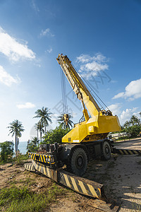 有上升的伸缩臂的黄色汽车起重机在户外 建筑工地上的移动式建筑起重机 起重机在施工大楼下等待工作 重工业蓝色活动地面力量机器柴油机背景图片