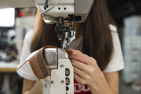 皮革车间的缝纫机在用手处理鞋子的皮革细节 女鞋厂有缝纫机的手生产商业行动作坊缝纫材料拉链家具金属裁缝背景图片