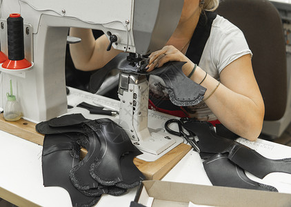 皮革车间的缝纫机在用手处理鞋子的皮革细节 女鞋厂有缝纫机的手拉链工艺商业衣服压缩缝纫裁缝金属制造业行动背景图片