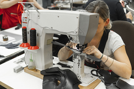 皮革车间的缝纫机在用手处理鞋子的皮革细节 女鞋厂有缝纫机的手机器裁缝制造业奶牛压缩材料水牛金属工厂衣服背景图片