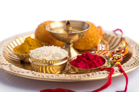 印度节 Rakhi与稻谷 库姆库姆 甜食和diya以优雅的拉基为盘子 传统的印度手腕带 象征着兄弟姐妹之间的爱粮食细绳崇拜庆典金背景