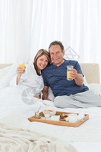 床上早餐可爱的情侣在床上吃早餐盘子男性老年面包夫妻玻璃男人女士水果微笑背景