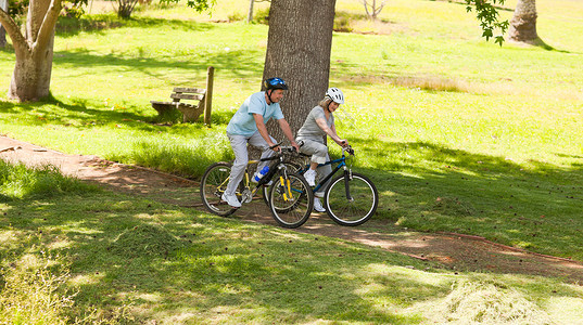 退休夫妇在户外骑山车两个人公园男性女性享受微笑女士夫妻老年农村背景图片