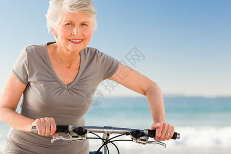 骑自行车的老年妇女男人乐趣家庭退休运动闲暇夫妻海滩背景图片