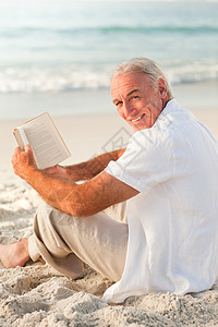 男人在海滩上看书海浪男性白色老年海岸生活日出退休日落孤独背景图片