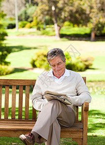 男人看报纸相机农村阅读男性座位微笑退休公园背景图片