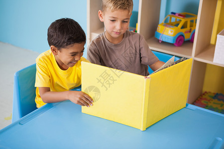 可爱的小男孩在教室桌上的书桌阅读早教男生教育桌子混血文学幼儿园故事书课堂男性背景图片