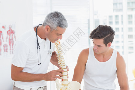 医生向病人展示解剖脊椎压力解剖学男性互动讨论痛苦房间理疗疝气治疗背景图片