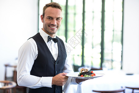 服务员显示菜盘快乐男人领结微笑酒店食物餐厅晚餐男性服务背景图片