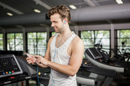 男人在跑步机上听音乐屏幕男性控制台训练耳机听力健身室健身闲暇电话背景图片