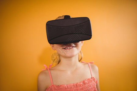 使用虚拟现实设备的女孩Name耳机娱乐服装童年技术休闲未来派电子女性黄色背景图片