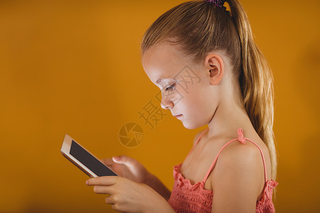 小女孩使用平板电脑女孩头发童年专注黄色幸福技术微笑滚动触摸屏背景图片