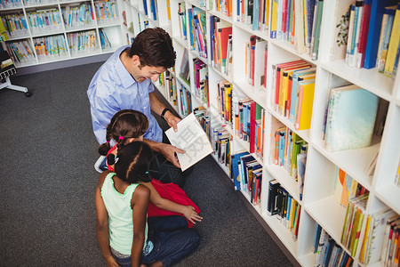 故事图书素材男人为两个孩子读一本书短发黑色棕色头发书柜学习女性地面知识文学背景