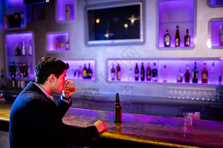 坐着喝酒的男人在酒吧柜台喝酒的男背景