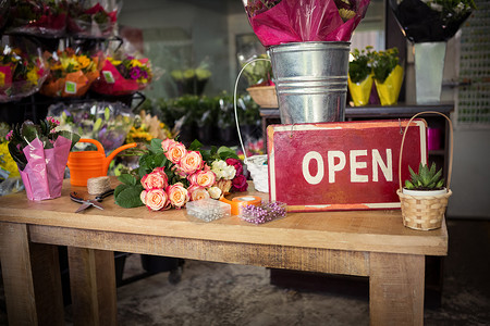 玫瑰标志在木制桌子上打开标牌标志招牌中心花园花艺植物零售店铺花瓶丝带背景