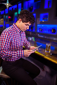 酒吧店牌素材在酒吧柜台使用数字平板牌的男子庆典技术沟通架子娱乐玻璃服装夜生活派对文化背景